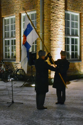 Evl Janne Oksanen luovuttaa ja evl Jukka Kentala vastaanottaa lipun 19.12.2014 Kivääritehtaan aamuhämärässä.